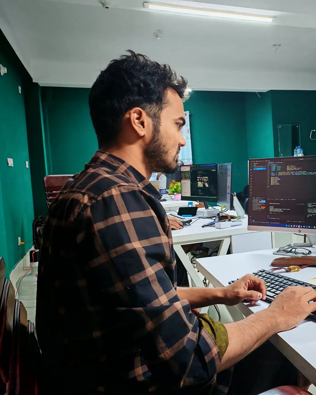Persona programando de noche frente a un monitor con código en pantalla